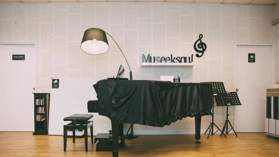 斗南教室大琴房——黑色琴罩下的平台鋼琴、弧形立燈與牆上的 Museeksoul 字樣